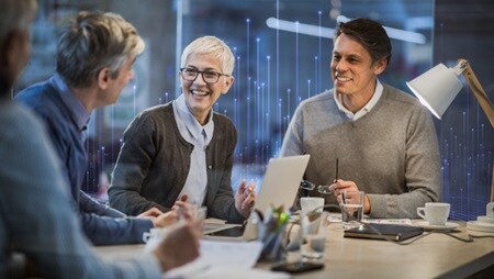 Employees smiling and talking while seated at a table for a meeting