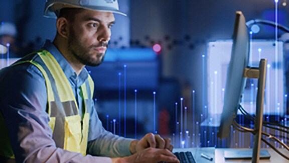 Johnson Controls technician using a desktop, overlaid with a graphic of transmission nodes in the backgroound