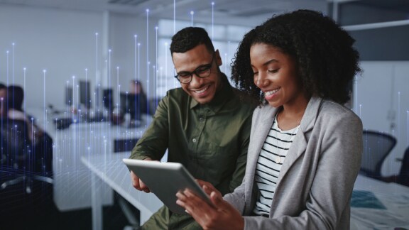 A woman and a man looking at a tablet in an office and smiling