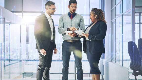 Two men and a woman standing and chatting in an office passage