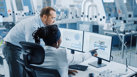 A woman pointing something on a computer to a man beside her